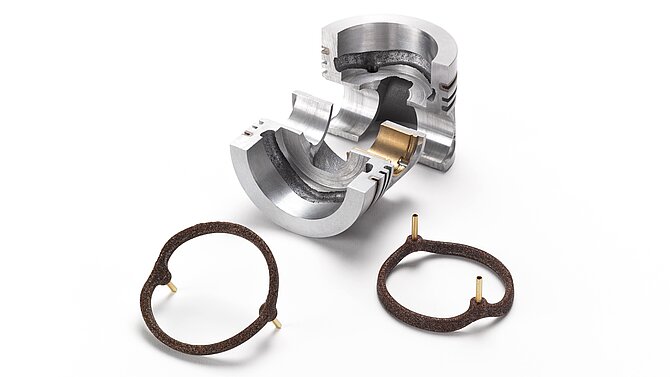 Ein silbernes Metallstück und braune Salzkerne für die Gießereitechnik