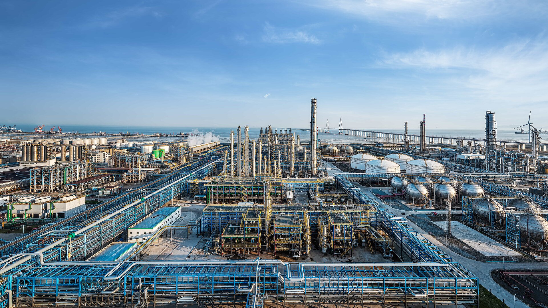 Aerial panoramic view of a massive coastal oil refinery and petrochemical industrial complex.