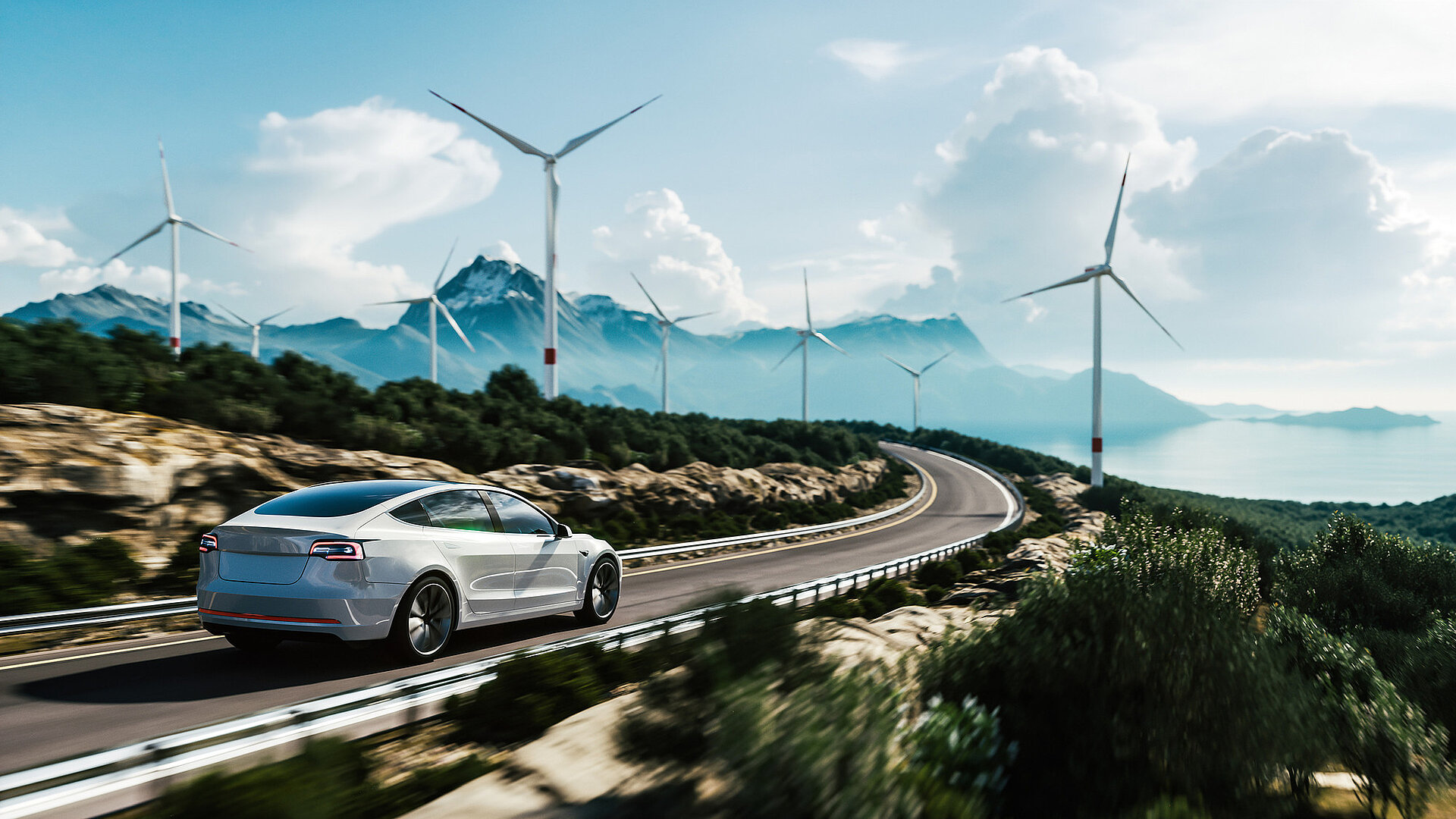 An electric car drives along a mountainous country road with wind turbines in the background.